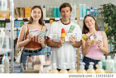 Father, mother and daughter choose different products together in modern pharmacy 134191824