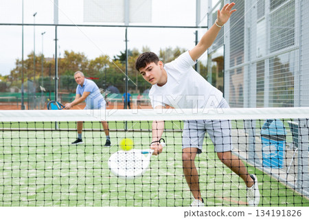 Young focused guy playing paddle tennis outdoors 134191826