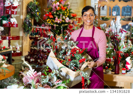 Portrait of a woman seller standing with a basket of Christmas decorations Portrait of a woman seller standing with a basket of Christmas decorations 134191828