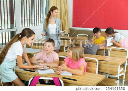 Concentrated preteen girls and boys solving teacher assignments in groups Concentrated preteen girls and boys solving teacher assignments in groups 134191858