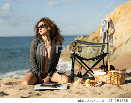 Attractive businesswoman kneeling on sandy beach 134191888