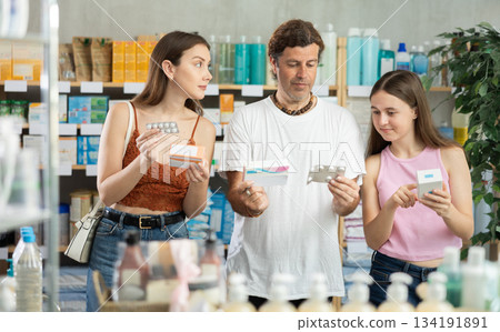 Father, mother and daughter choose pills together at drugstore 134191891