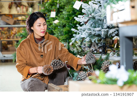 Asian woman choosing christmas decorations Asian woman choosing christmas decorations 134191907