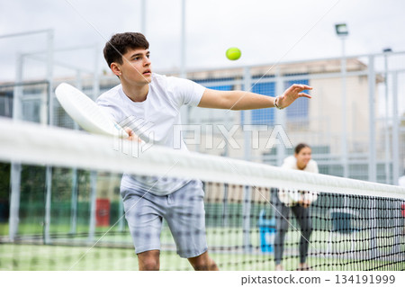 Focused teenager playing paddleball match on outdoor court Focused teenager playing paddleball match on outdoor court 134191999