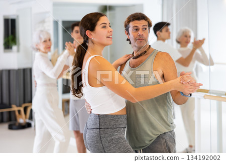 Active sportive men and women enjoying of partner dance in dance studio Active sportive men and women enjoying of partner dance in dance studio 134192002