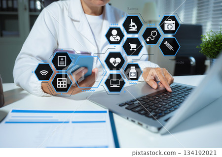 Doctor working on laptop computer and tablet and medical stethoscope on clipboard on desk, electronics medical record system EMRs concept. Doctor working on laptop computer and tablet and medical stethoscope on clipboard on desk, electronics medical record system EMRs concept. 134192021