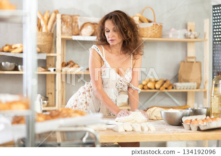 Sexy woman kneading dough with her hands on the kitchen table of bakery 134192096