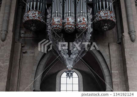 Grand pipe organ in Trier Cathedral features ornate floral carvings and dramatic suspended structure rising above stone arches Grand pipe organ in Trier Cathedral features ornate floral carvings and dramatic suspended structure rising above stone arches 134192124