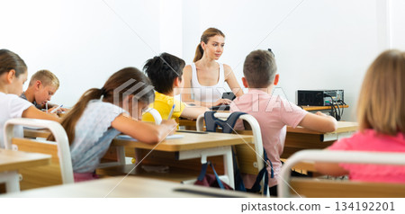 Female schoolteacher using computer during lesson with children Female schoolteacher using computer during lesson with children 134192201