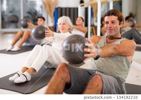 Men and women doing pilates exercises with fitness ball at gym Men and women doing pilates exercises with fitness ball at gym 134192210