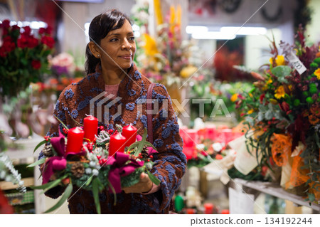 Woman buying New Year decor at flower shop Woman buying New Year decor at flower shop 134192244