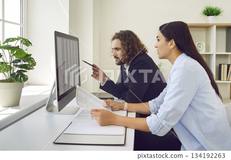 Two young accountants working with business spreadsheets on their office computer Two young accountants working with business spreadsheets on their office computer 134192263