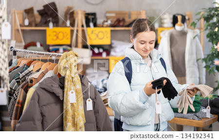 Teenage girl choosing a glove in a clothing store 134192341