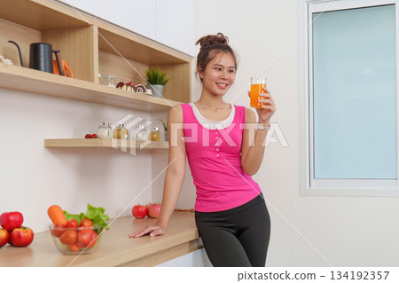 Refreshing Drink. Woman enjoying healthy juice in modern kitchen. Refreshing Drink. Woman enjoying healthy juice in modern kitchen. 134192357
