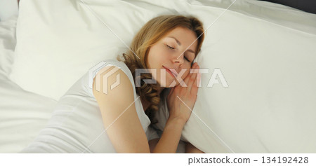 Woman sleeping lying in bed on white soft comfortable pillow in bedroom at home 134192428