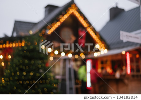 Abstract, blurry background of a Christmas market with bokeh lights on the roofline and tree, festive winter shopping Abstract, blurry background of a Christmas market with bokeh lights on the roofline and tree, festive winter shopping 134192814