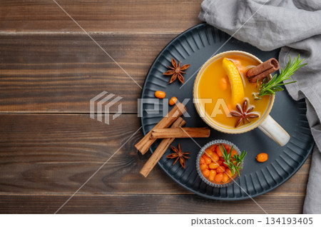 Sea buckthorn herbal tea in a cup on a black plate on a wooden background 134193405