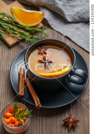Sea buckthorn herbal tea in a black cup on a wooden background with spices 134193406