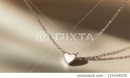 Silver heart necklace resting on a soft surface in natural light showcases elegance and simplicity Silver heart necklace resting on a soft surface in natural light showcases elegance and simplicity 134194070
