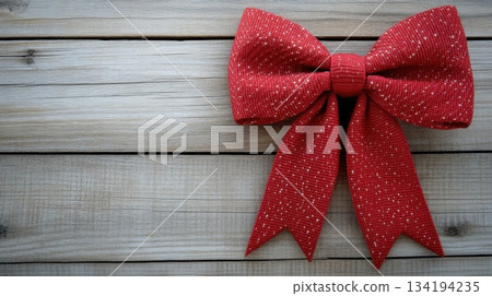 Red fabric bow placed on rustic wooden surface, perfect for crafts or holiday decorations Red fabric bow placed on rustic wooden surface, perfect for crafts or holiday decorations 134194235