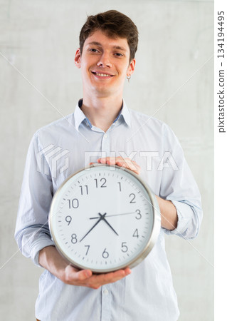 Young guy posing with clock in studio 134194495