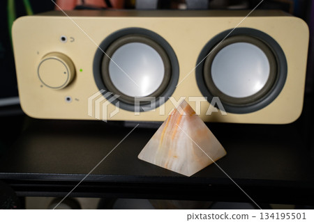 Agate pyramid on table in front of white speaker Agate pyramid on table in front of white speaker 134195501