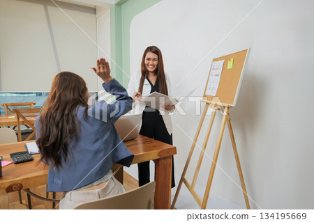 Busy office women meet for work, team members collaborate, discussing market strategy, presenting project data on corkboard, sharing ideas enthusiastically during productive conference room meeting. Busy office women meet for work, team members collaborate, discussing market strategy, presenting project data on corkboard, sharing ideas enthusiastically during productive conference room meeting. 134195669