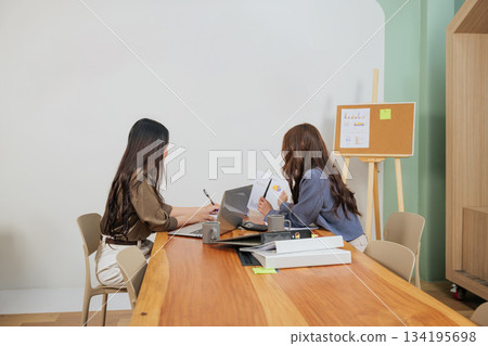 Busy office women work, team members meet, analyze market data on laptop and charts, discussing graphs, productive business collaboration in modern professional conference room environment. Busy office women work, team members meet, analyze market data on laptop and charts, discussing graphs, productive business collaboration in modern professional conference room environment. 134195698