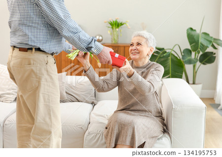 Senior man giving flowers gift box to old woman. Happy family couple. Husband wife with present tulip flowers bouquet celebrating women day birthday family wedding date Valentines day. In love people 134195753