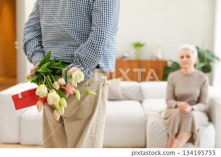 Senior man giving flowers gift box to old woman. Happy family couple. Husband wife with present tulip flowers bouquet celebrating women day birthday family wedding date Valentines day. In love people Senior man giving flowers gift box to old woman. Happy family couple. Husband wife with present tulip flowers bouquet celebrating women day birthday family wedding date Valentines day. In love people 134195755