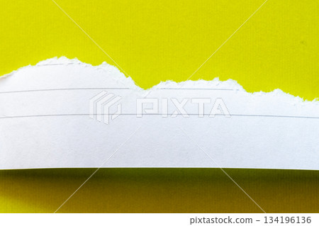 Ripped white paper with lined texture on a bright yellow background. The torn edge creates a contrast between the two colors. 134196136