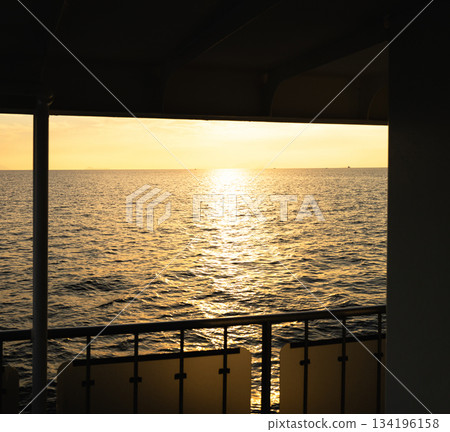 An image of someone looking out at the sea at dusk from a ferry just before sunset. An image of someone looking out at the sea at dusk from a ferry just before sunset. 134196158