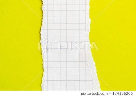 Ripped white paper with squared texture on a bright yellow background. The torn edge creates a contrast between the two colours. 134196206