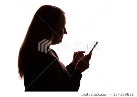 Silhouette of young woman using smartphone on white background 134196651