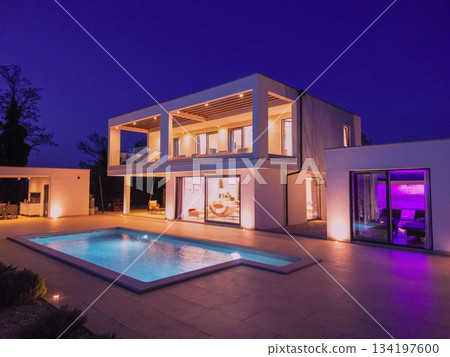 Modern luxury villa illuminated at night with pool, terraces, and contemporary architecture. Warm lighting and elegant outdoor living create a stylish and sophisticated atmosphere 134197600