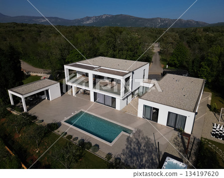 Modern luxury villa with pool, terraces, and clean minimalist architecture captured by drone. Bright sunny day, surrounding greenery, and contemporary outdoor living areas Modern luxury villa with pool, terraces, and clean minimalist architecture captured by drone. Bright sunny day, surrounding greenery, and contemporary outdoor living areas 134197620