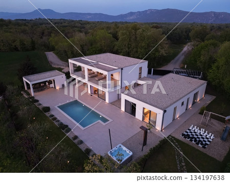 Modern luxury villa illuminated at night with pool, terraces, and contemporary architecture. Warm lighting and elegant outdoor living create a stylish and sophisticated atmosphere Modern luxury villa illuminated at night with pool, terraces, and contemporary architecture. Warm lighting and elegant outdoor living create a stylish and sophisticated atmosphere 134197638