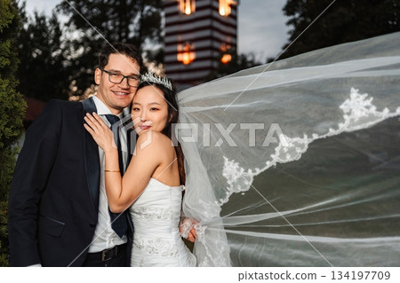 Interracial couple celebrating wedding day with flowing veil 134197709