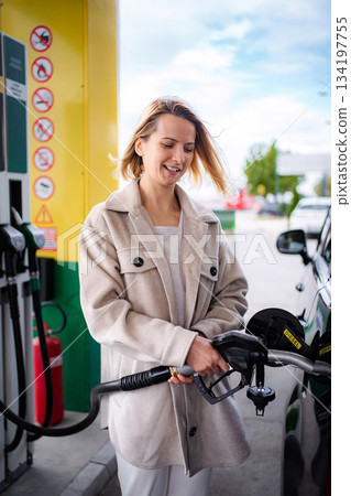 Woman smiling fueling diesel car at gas station Woman smiling fueling diesel car at gas station 134197755