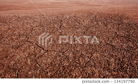 Closeup of cracked and dry soil surface with a barren desert land background. Concept of Extreme Weather Closeup of cracked and dry soil surface with a barren desert land background. Concept of Extreme Weather 134197790