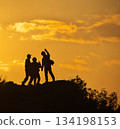 Silhouettes of two people jumping against the backdrop of the setting sun 134198153