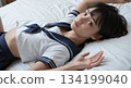 一個穿著水手服的高中女生累了，躺在床上。 134199040
