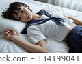 一個穿著水手服的高中女生累了，躺在床上。 134199041