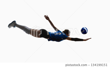 Female volleyball player diving with elevated legs reaching toward ball. 134199151