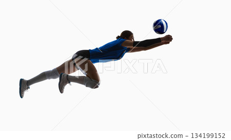 Airborne volleyball player diving fully extended toward incoming ball. 134199152