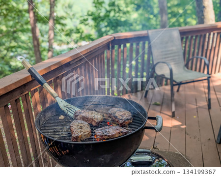 Summer picnic with small charcoal grill and steaks on deck 134199367