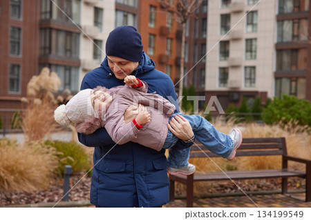 Father playing with happy daughter, having fun outdoors in warm winter clothing 134199549