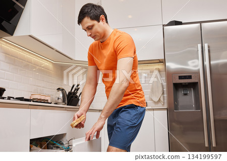 Man opening kitchen drawer with a sponge for cleaning or tidying 134199597