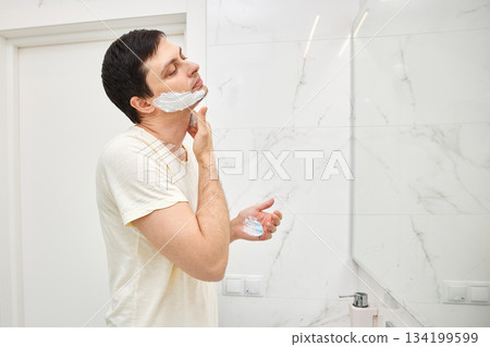 Man applying shaving foam to his face for a morning shave routine 134199599