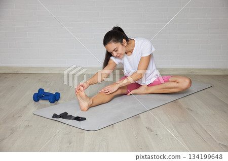 Woman performing a seated forward bend for flexibility and health Woman performing a seated forward bend for flexibility and health 134199648